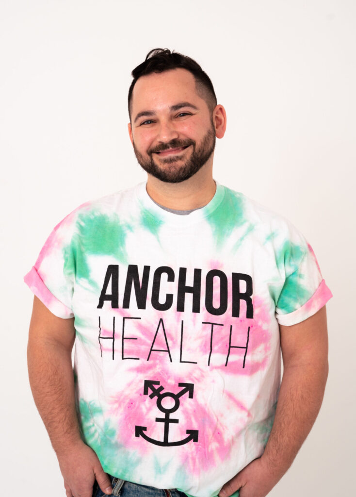 A man wearing an Anchor Health t-shirt smiling at the camera.