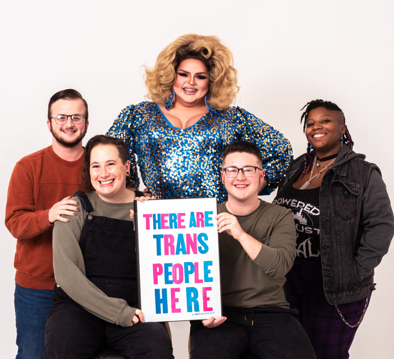 A group of LGBTQ people holding a poster of H. Melt's quote: "There are trans people here."